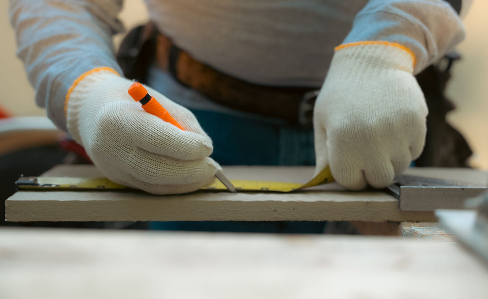 RoofCo siding contractor wearing white protective gloves using a tape measure and pencil to mark a piece of siding material.