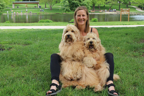 Two adorable Doodles with their owner in front of a lake