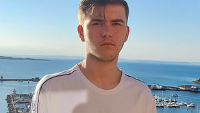 Picture of Ethan Vassilev, teenage boy standing in front of water and boats