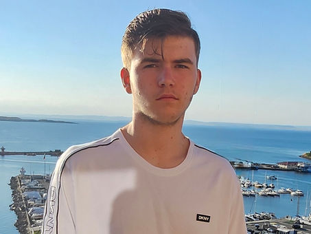 Picture of Ethan Vassilev, teenage boy standing in front of water and boats