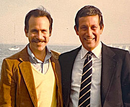 Older photo of Allan Shedlin and his brother Vic with the ocean and sailboats in the distance at their backs