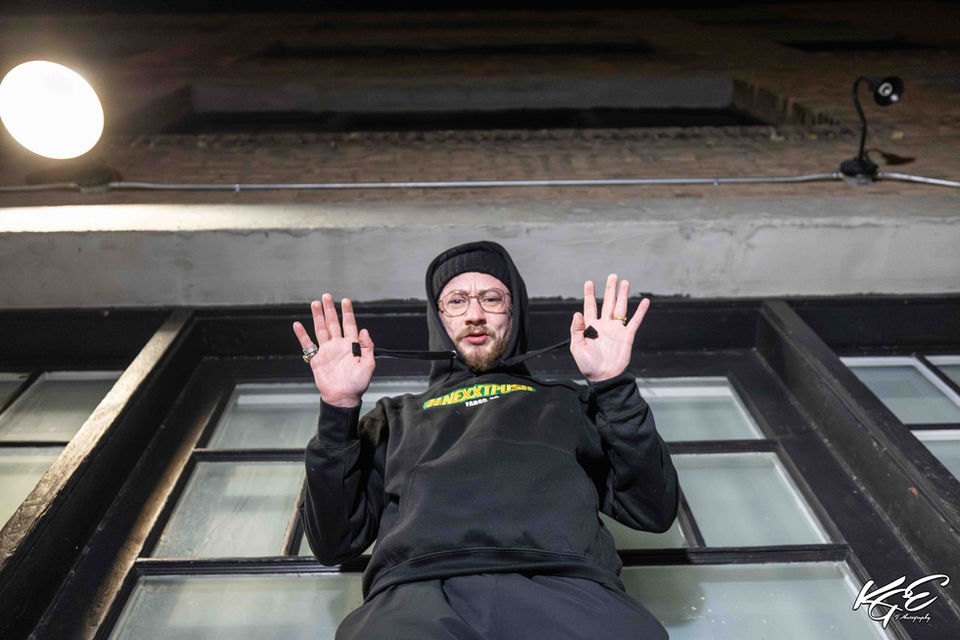 Jantzen in a downtown Fargo alley, shot from below with a wide-angle lens showing both him and the surrounding buildings. Captured by KGE Photography, part of The Wide View Project by Fargo photographer Kevin Eilenberg.