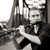 Photo of bandmember Skyler Blakeslee playing flute on a bridge