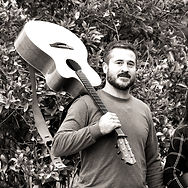 Photo of bandmember Vince Wolfe carrying a guitar on his shoulder