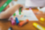A little boy sitting at a table with crayons
