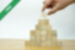 A hand placing a piece of wood into a pyramid
