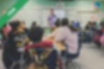 Students in a classroom with a teacher presenting