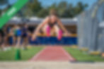 An athlete mid-jump in a long jump competition