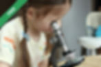A young girl looking into a microscope