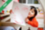 A girl holding up a drawing