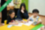 Children drawing with a teacher at a table
