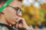 A boy with glasses holding his face