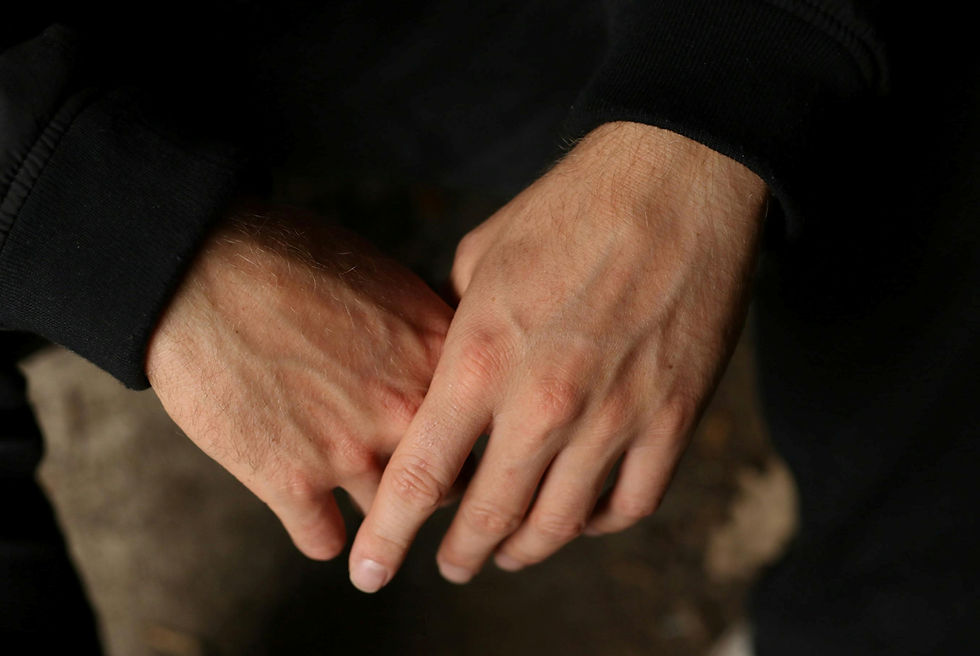 검정 옷을 입은 사람이 손을 맞잡고 있는 모습. 어두운 배경에 두 손이 강조되어 따뜻하고 진지한 분위기를 전달한다.