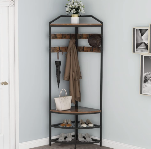 Black coat rack with brown coat, umbrella, hat, white bag, shoes, and flowers in a light blue entryway.