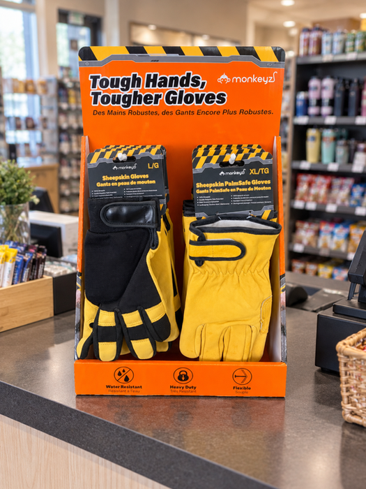 Black and yellow work gloves displayed on a retail countertop display with product signage.