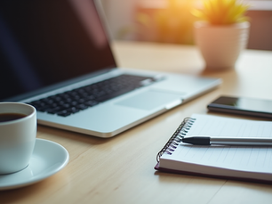 Eye-level view of a desk with a laptop, notebook, and coffee cup, symbolizing social media planning