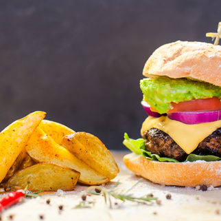 Professional food photograph of a gourmet burger and potato wedges for restaurant marketing.