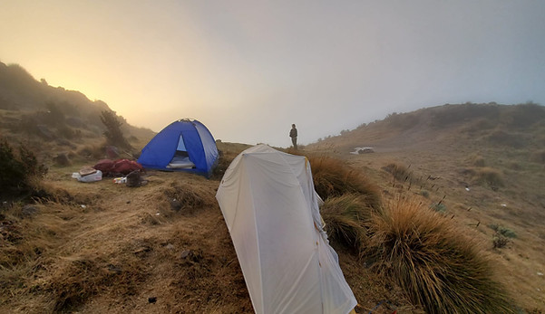 a blue and a grey tent with sunset