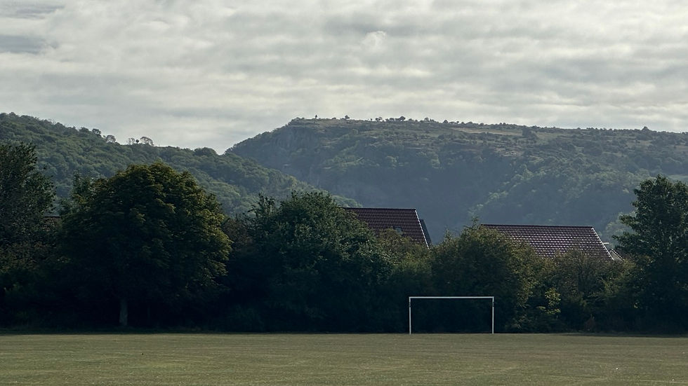 Distant view of Cheddar gorge with playing fields in foreground