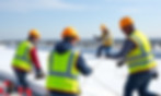 4 guys in hard hats with safety vests installing and attaching white tpo on a large flat r