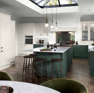 Clifden painted Heritage Green and Porcelain. Worktop is Dekton Stonika XGloss Collection Natural18c2 and backsplash is Rough Old Glass Vintage. A beautiful yet functional integrated pantry unit features double panel doors. Add a touch of luxury with a canopy to house a recessed extractor fan and incorporate an overmantle shelf to achieve a high-end look.