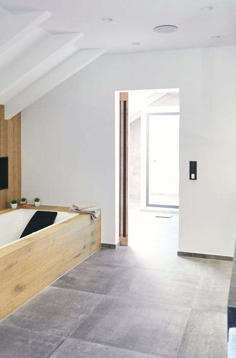 Großzügiges Badezimmer mit eingelassener Badewanne, Holzverkleidung und beleuchteter Wandnische, individuelle Badgestaltung von Biermann