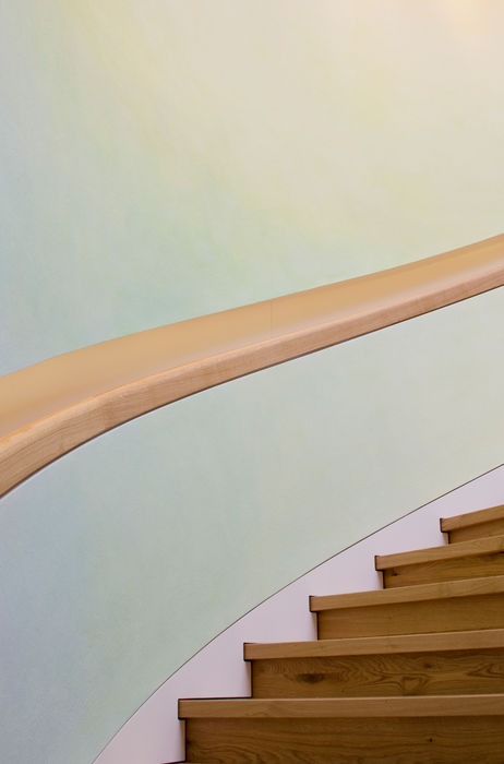 Detailaufnahme eines gebogenen Holzhandlaufs an einer Wendeltreppe, präzise gefertigte Innenausbau-Lösung