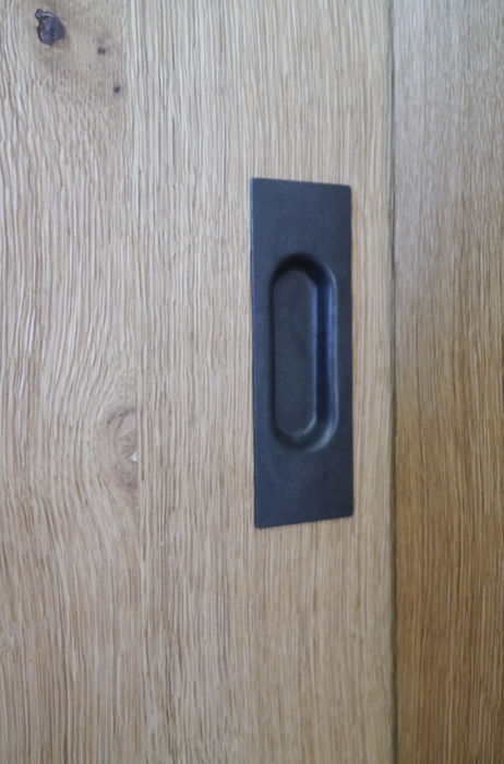 Detail einer Schiebetür aus Alteiche mit eingelassenem schwarzem Griff, hochwertige Verarbeitung im Innenausbau