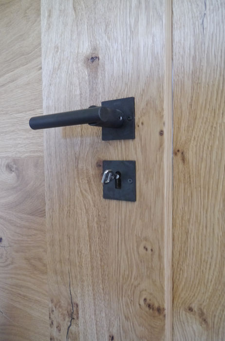 Detail einer Zimmertür aus Alteiche mit modernem schwarzem Türgriff und Beschlag, langlebige Innenausbau-Lösung für Privatkunden