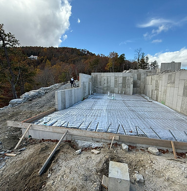 Slab foundation installation and rebar work being done on the top of a mountian in Bevard, NC. Residnetial concrete poruing for a building in Bevard, by a concrete contractor and his crew. White and gray walls with the meatl rebar being installed and the preping stage of the concrete project.