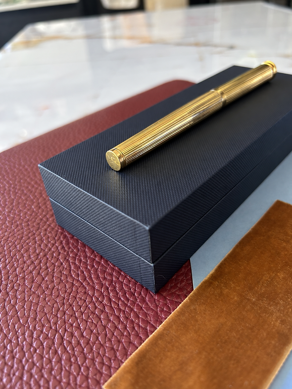 Gold pen resting on a matte black gift box