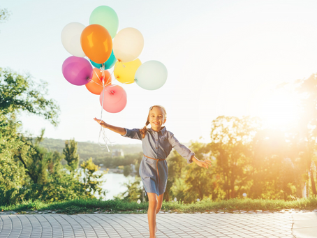 Happy girl holding colorful balloons in the city park