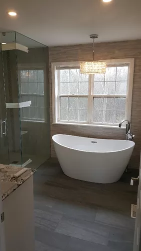 A finished bathroom renovation featuring a curbless shower and standalone bathtub.