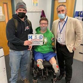 Josh Tarsky standing next to a child in a wheelchair and another adult