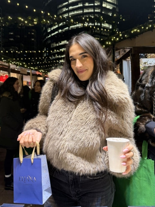 A woman in a fur coat at a local outdoor maker's market event with a blue bag from Eliana Curated.