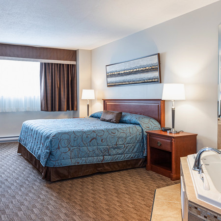 Tranquil ambiance in our Jacuzzi King room: king bed, lounge chairs, jet jacuzzi tub, and refreshing open windows.