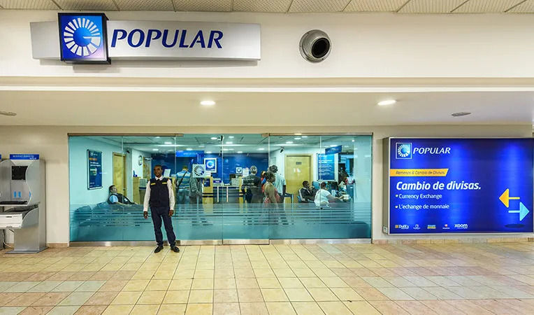 Banco Popular agency in the Dominican Republic with a blue sign the currency exchange and a guard on the front