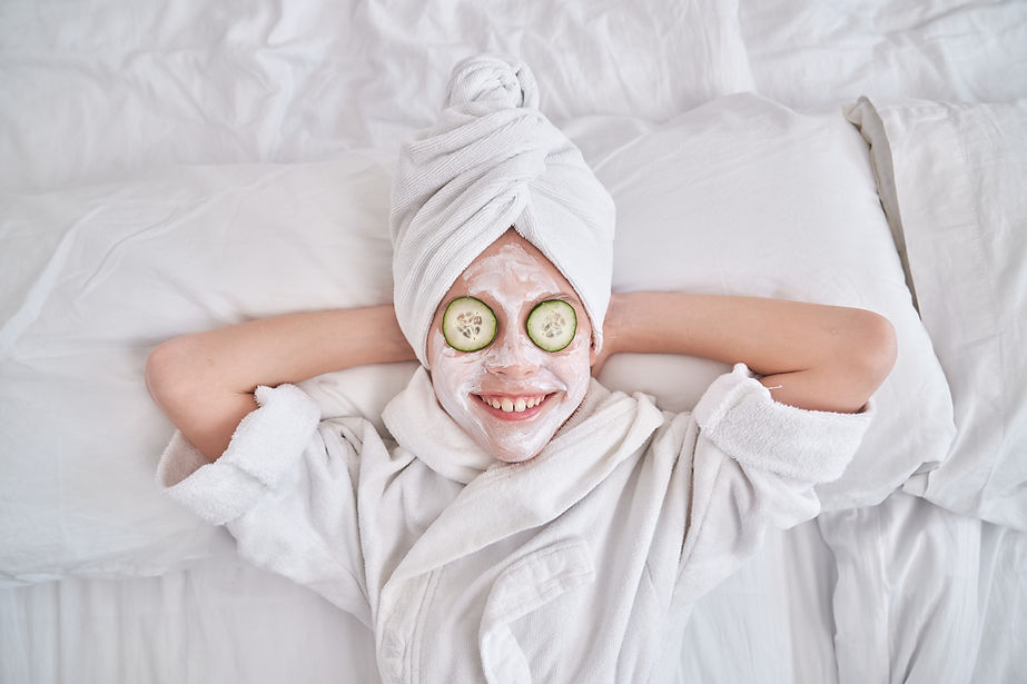 Smiling teen relaxing with a hydrating facial mask for natural skin care, and spa towel at Vitaflow Wellness