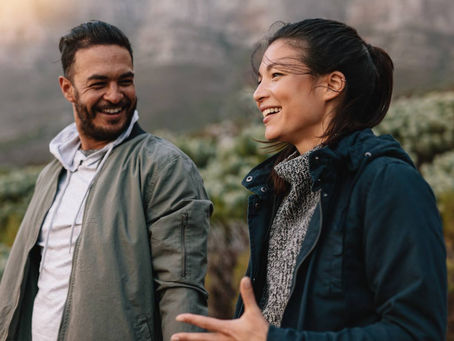 Two people walking outdoors, smiling and talking together, showing how supportive connection ties love and mental health to everyday well-being.