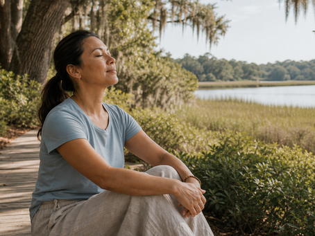 Adult sitting quietly beside a shaded outdoor path and water view, practicing mindfulness for stress relief.