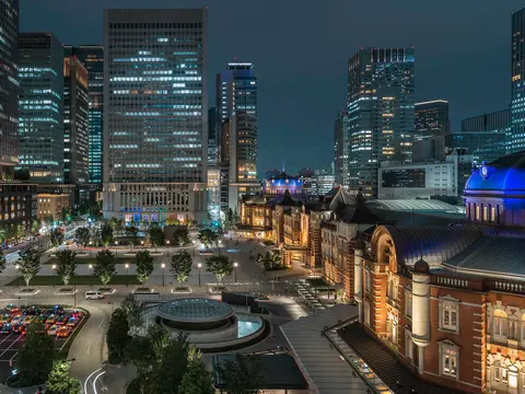 Tokyo Station at night with illuminated red-brick facade and Marunouchi skyscrapers in the background