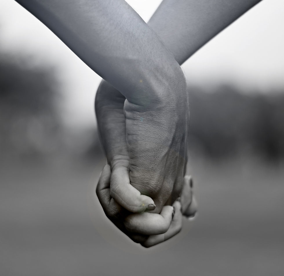 Eye-level view of two hands resting close together beside a warm cup of tea.