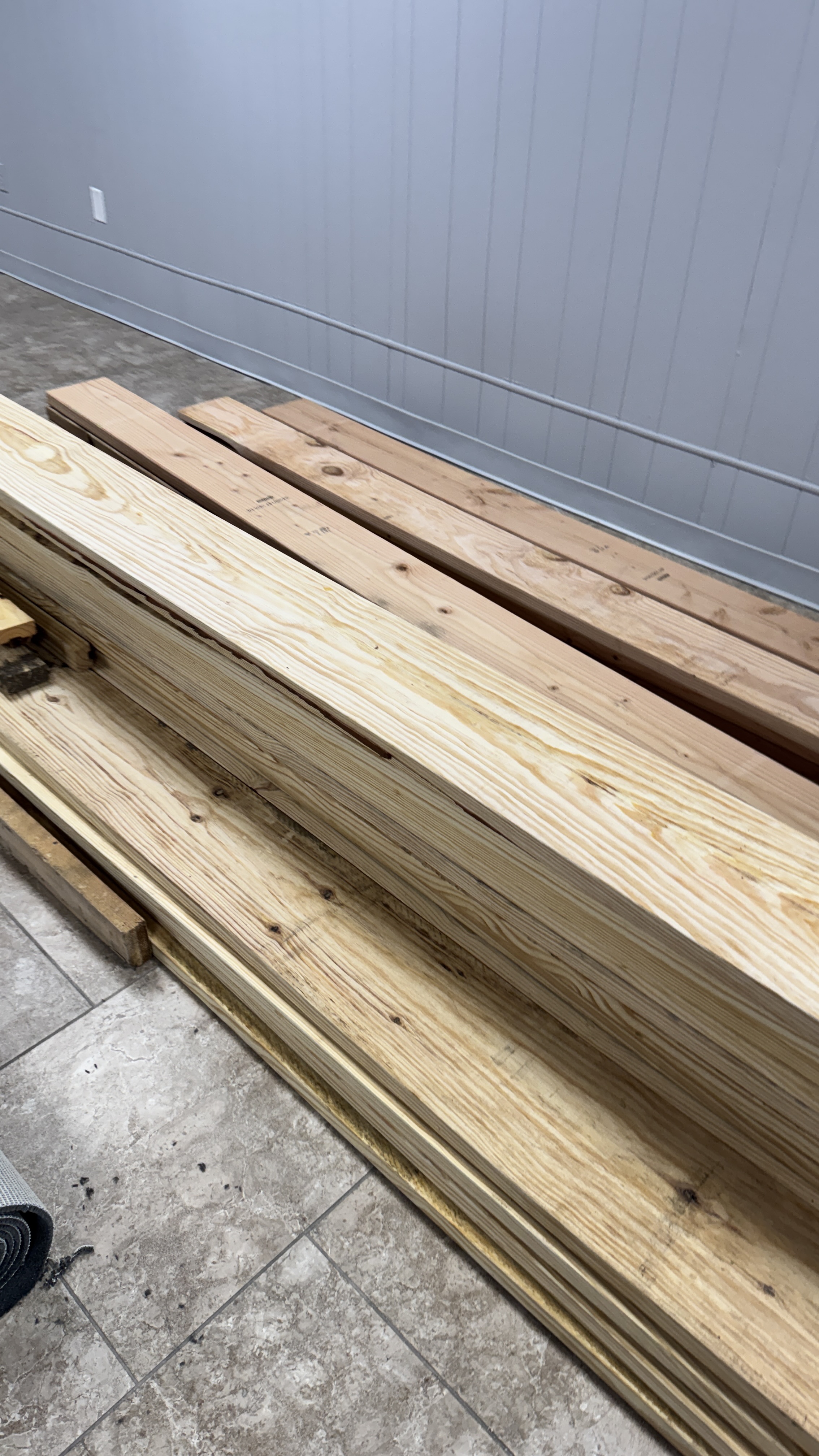 Stack of construction lumber on a tile floor, shown as an example of wood not suitable for freshwater aquariums.