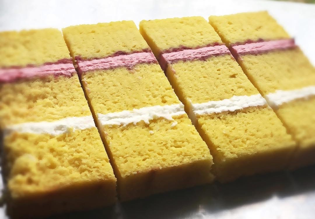 Four slices of golden cake with pink and white filling between the layers
