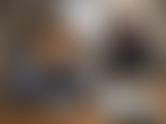 A weary caregiver rests her head in her hands, surrounded by medical supplies, as she contemplates her responsibilities while attending to a person in a wheelchair watching TV.