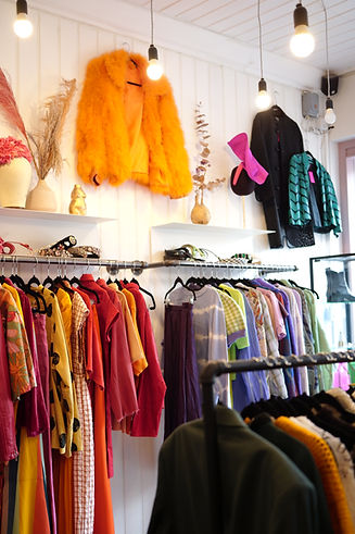 Retail rails in the Dressing Room. Orange fluffy jacket on wall