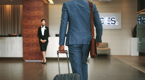 Business man walking into hotel with luggage.