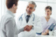 Doctor shaking hands with a patient nurse in background