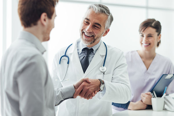 Doctor shaking hands with a patient nurse in background