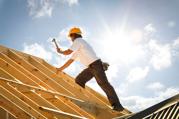 Construction worker building roof on sunny day